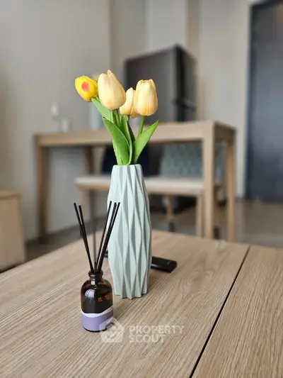 Modern interior with stylish vase and flowers on wooden table, showcasing elegant decor.
