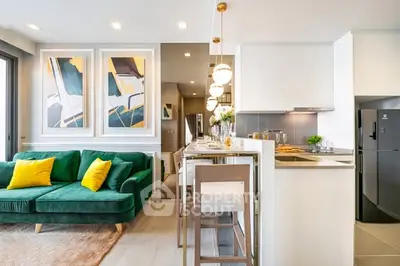 Modern open-layout living room and kitchen with stylish decor and green sofa.
