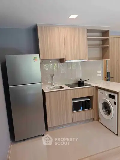 Modern kitchen with sleek appliances and compact design, featuring a fridge, washing machine, and microwave.