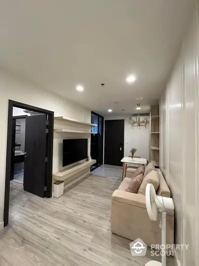 Spacious living room with modern design, elegant built-in fireplace, sleek hardwood floors, and contemporary lighting fixtures, leading to a cozy dining area.