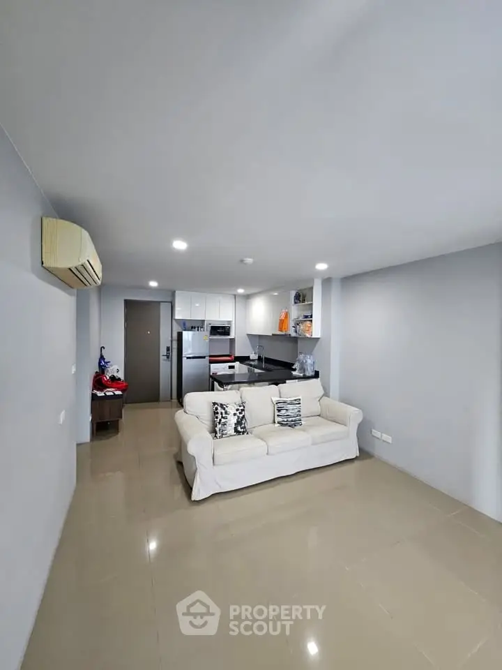 Modern open-layout living room with sleek kitchen and cozy sofa, perfect for urban living.