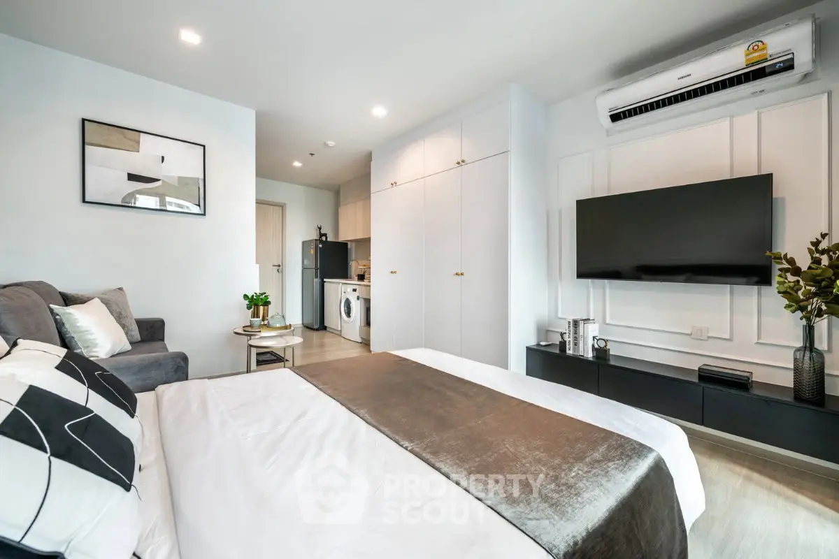 Modern studio apartment with sleek design, featuring a cozy bed, stylish living area, and compact kitchen.
