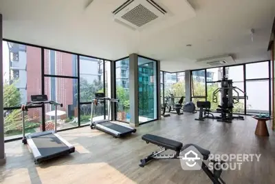 Modern gym with large windows and fitness equipment in luxury apartment building.