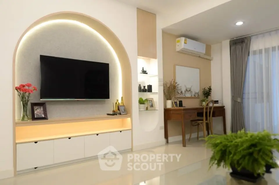Modern living room with stylish decor and elegant furniture, featuring a wall-mounted TV and ambient lighting.