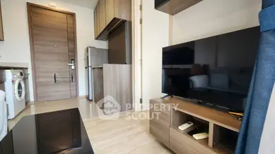 Modern apartment interior with sleek kitchen and cozy living area featuring a flat-screen TV.