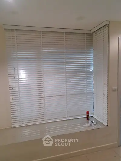 Modern interior with large window and white blinds in a cozy living space.