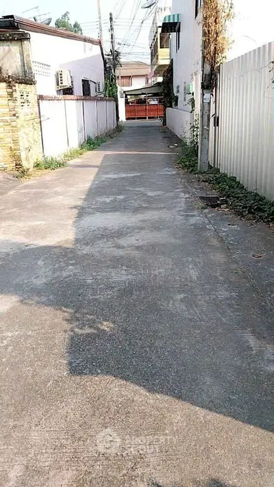 Quiet residential alleyway with gated entrance and surrounding walls