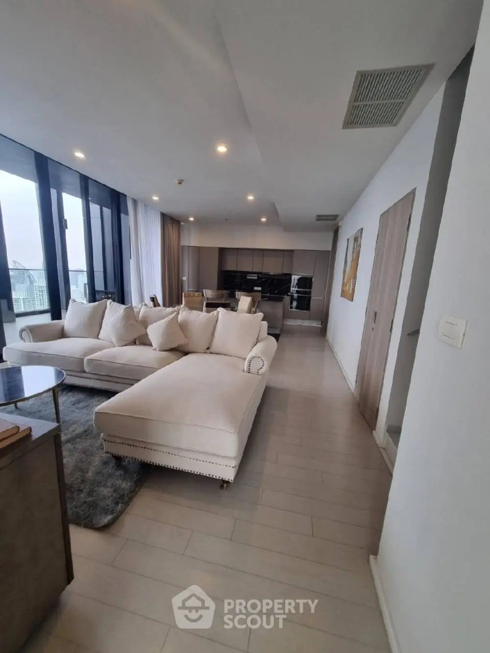 Luxurious open-plan living room with modern kitchen and stunning city view.