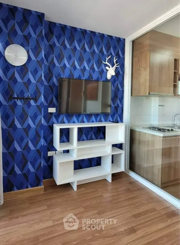 Modern living room with blue geometric wallpaper and sleek white shelving unit.