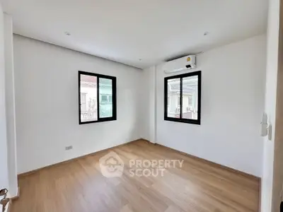 Spacious empty room with wooden flooring and large windows in modern home