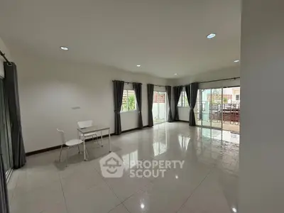Spacious living room with large windows and balcony access, perfect for natural light lovers.
