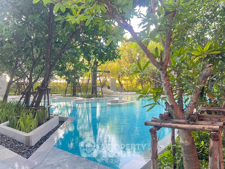 Luxurious outdoor pool surrounded by lush greenery in a serene real estate setting.