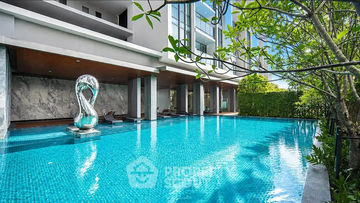 Luxurious modern apartment pool with elegant sculpture and lush greenery, perfect for relaxation and leisure.