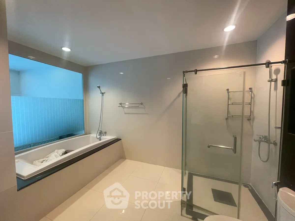 Spacious modern bathroom with bathtub and glass shower enclosure