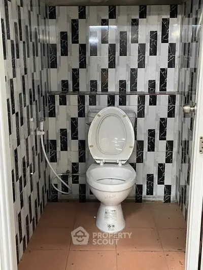 Compact bathroom with modern black and white tile design and toilet