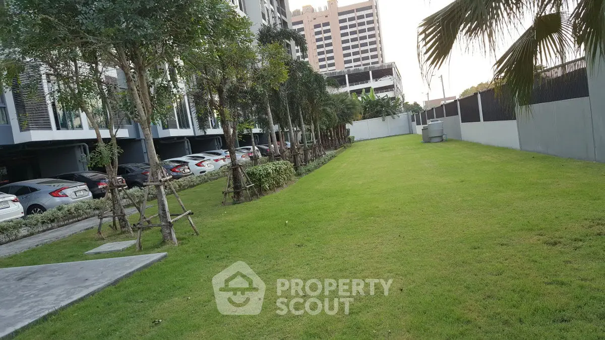 Spacious green garden area with adjacent parking in modern residential complex.