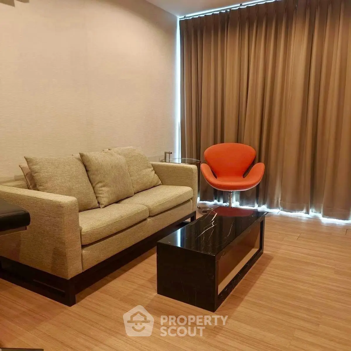 Modern living room with stylish sofa and chair, featuring elegant wooden flooring and floor-to-ceiling curtains.