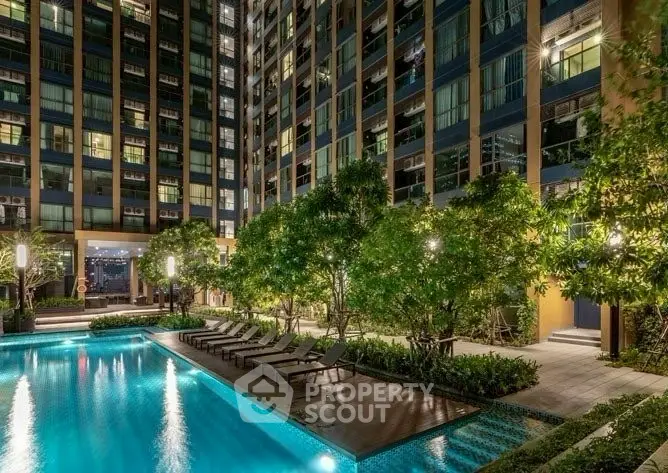Luxurious condominium with illuminated pool and lush greenery at night.