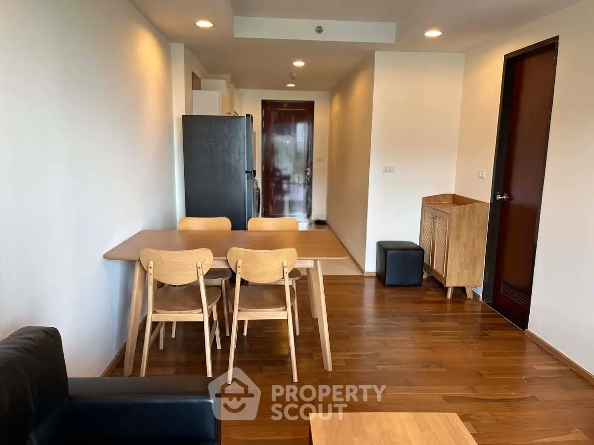 Modern dining area with wooden flooring and furniture in a cozy apartment setting.