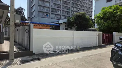 Modern urban building exterior with gated entrance and surrounding greenery.