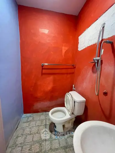 Vibrant red bathroom with shower and toilet, featuring unique wall design.