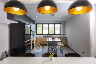 Modern kitchen with sleek design, featuring island and large windows for natural light.