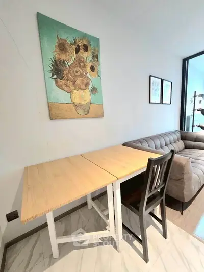 Modern living room with stylish sofa and wooden dining table, featuring elegant wall art and bright natural lighting.