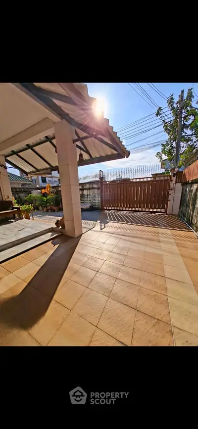 Spacious sunlit patio with tiled flooring and gated entrance, perfect for outdoor relaxation.