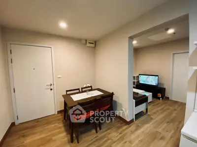 Modern dining area with wooden table and chairs, open layout to cozy living room.