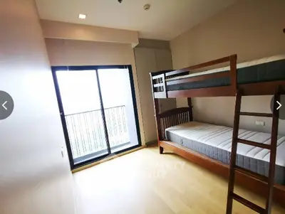 Bright bedroom with bunk beds and large window leading to balcony.