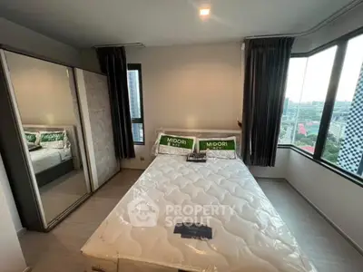 Modern bedroom with large windows and mirrored wardrobe in urban apartment.