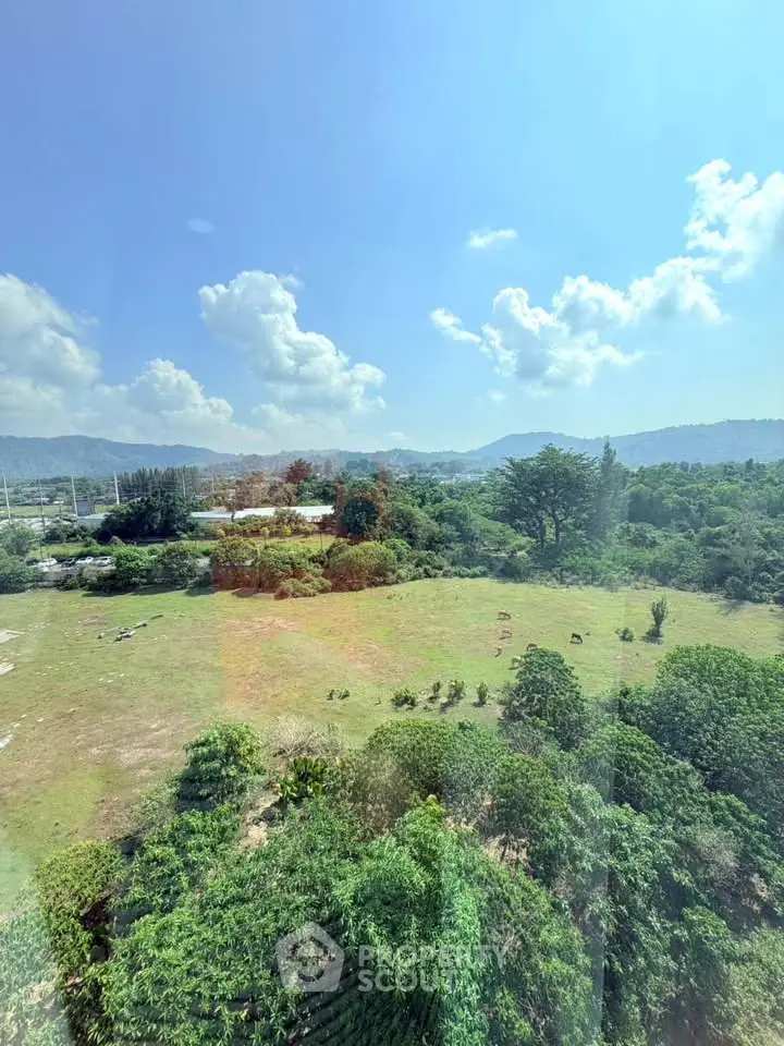 Scenic view of lush green landscape with distant hills under a clear blue sky, perfect for real estate development.