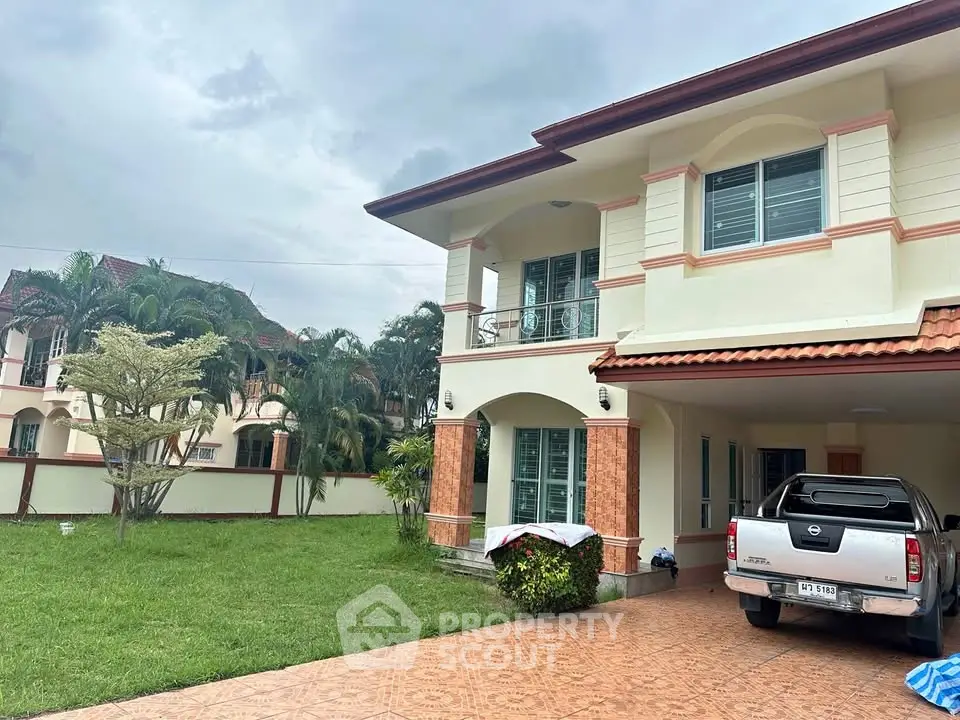 Spacious two-story house with lush garden and driveway in a serene neighborhood.