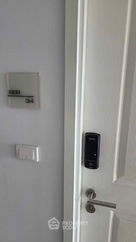 Modern apartment door with electronic lock and room number 34, showcasing security features.