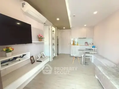 Modern living room with open kitchen, featuring sleek furniture and bright lighting.