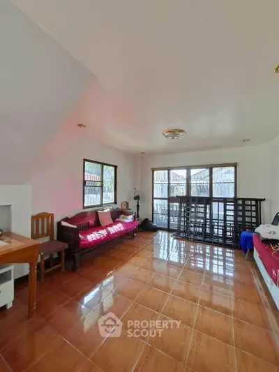 Spacious living room with natural light and tiled flooring, perfect for relaxation.