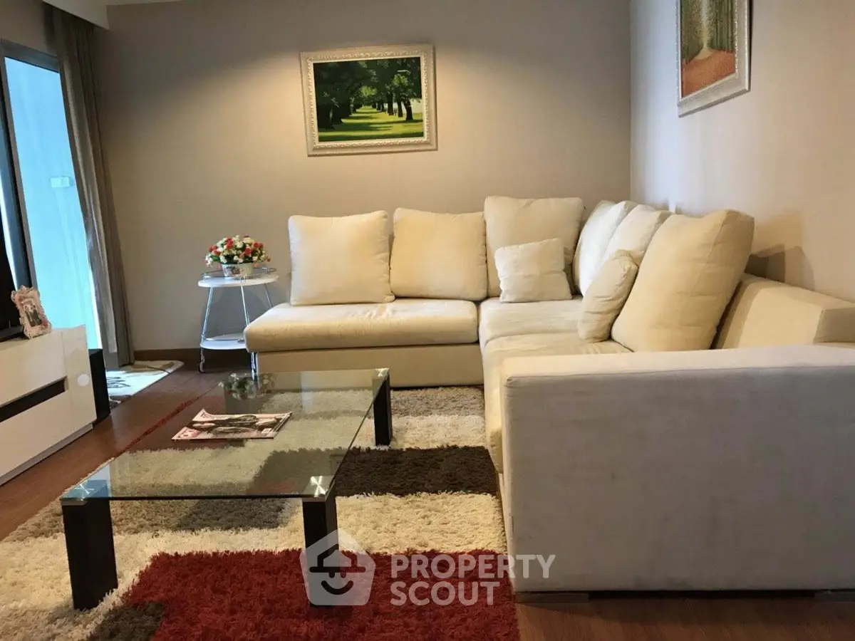 Elegant living room with plush white sectional sofa and glass coffee table, perfect for modern comfort.