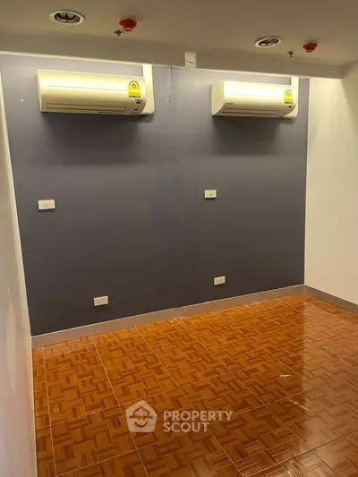 Spacious room with dual air conditioning units and wooden flooring