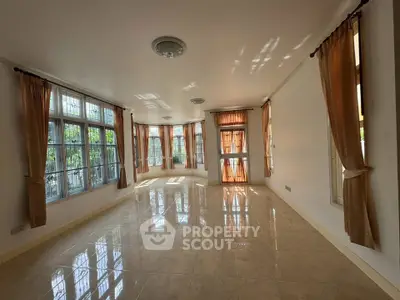 Spacious sunlit living room with large windows and elegant curtains