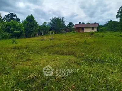 Expansive green land with a small house, perfect for development or agriculture.