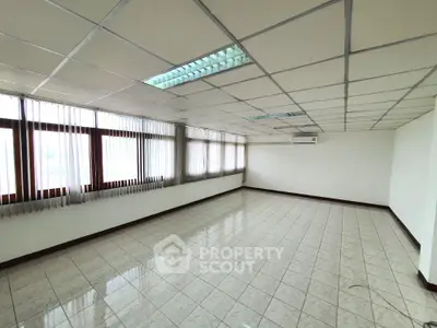 Spacious empty office space with tiled flooring and large windows
