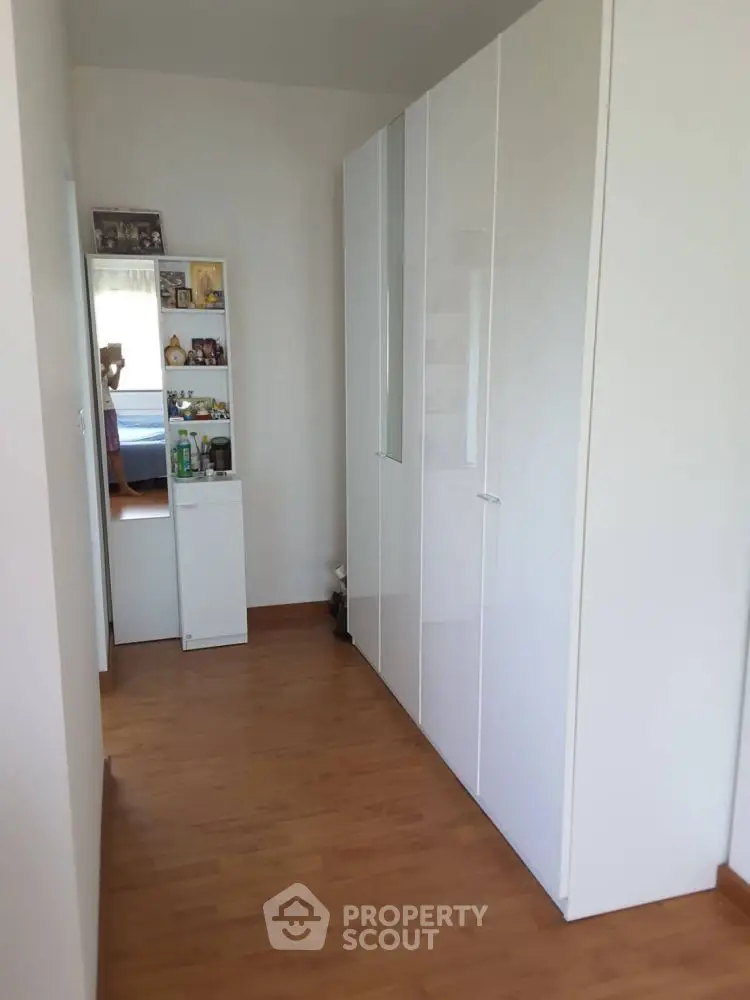 Spacious hallway with sleek white wardrobe and wooden flooring