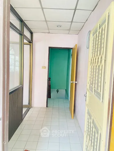 Simple hallway with tiled floor leading to a small room