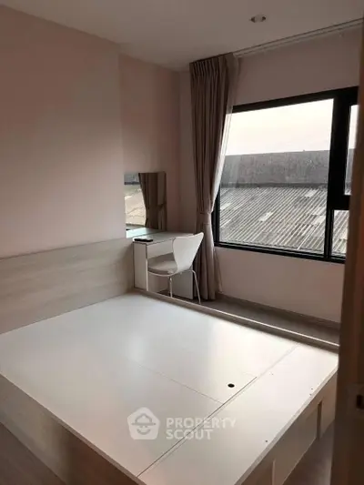Modern bedroom with large window and minimalist furniture, offering a bright and airy atmosphere.