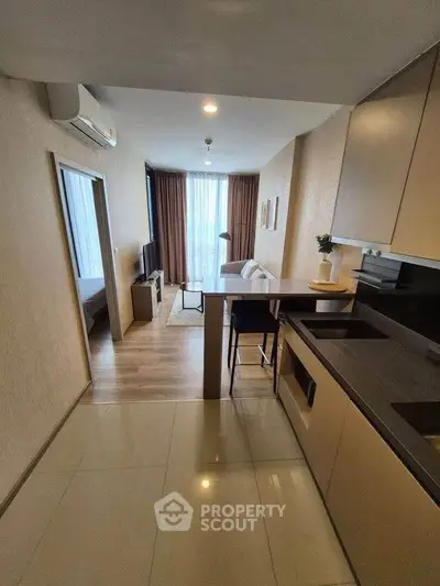 Modern open-plan living room with kitchen, featuring sleek design and natural light.