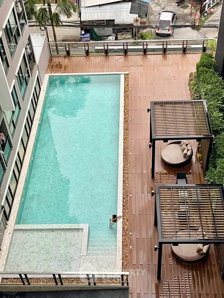 Luxurious apartment complex with a stunning outdoor pool and stylish seating area, perfect for relaxation.