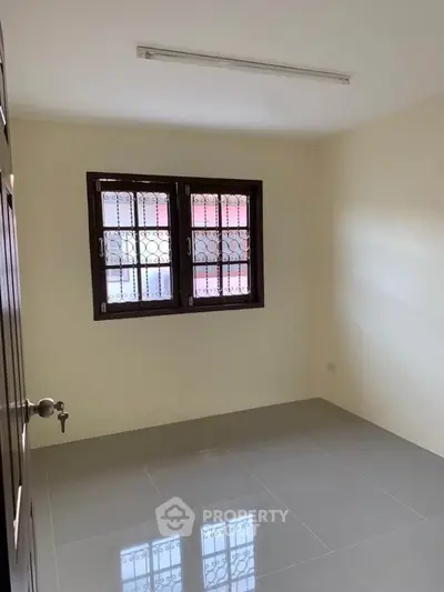 Spacious empty room with tiled floor and barred windows, perfect for customization.