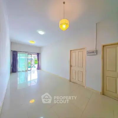 Spacious empty living room with glossy tiled floors and large windows for natural light.
