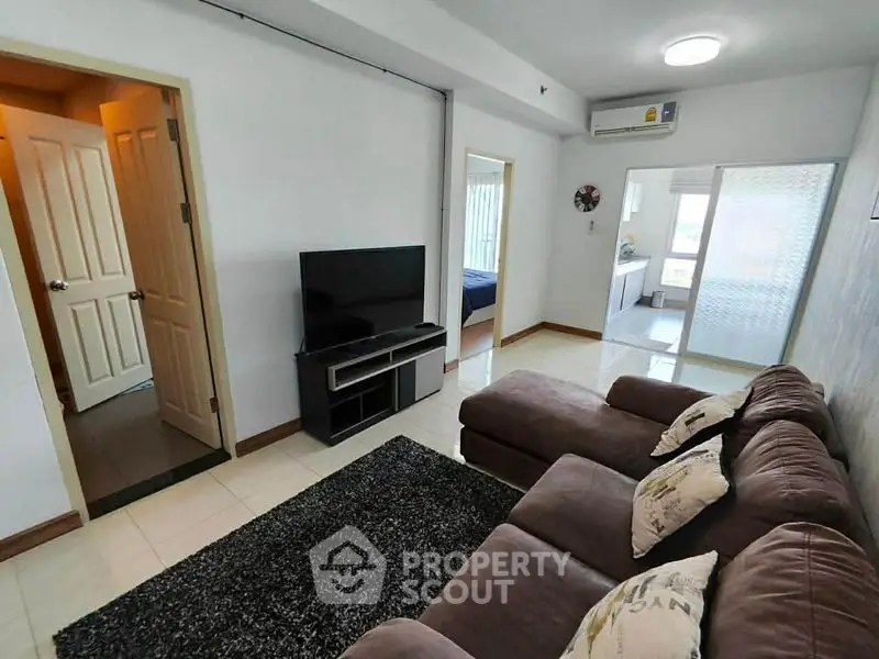 Spacious living room with modern decor and cozy seating in a well-lit apartment.