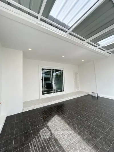 Spacious modern patio with sleek tile flooring and glass sliding doors, perfect for outdoor relaxation.